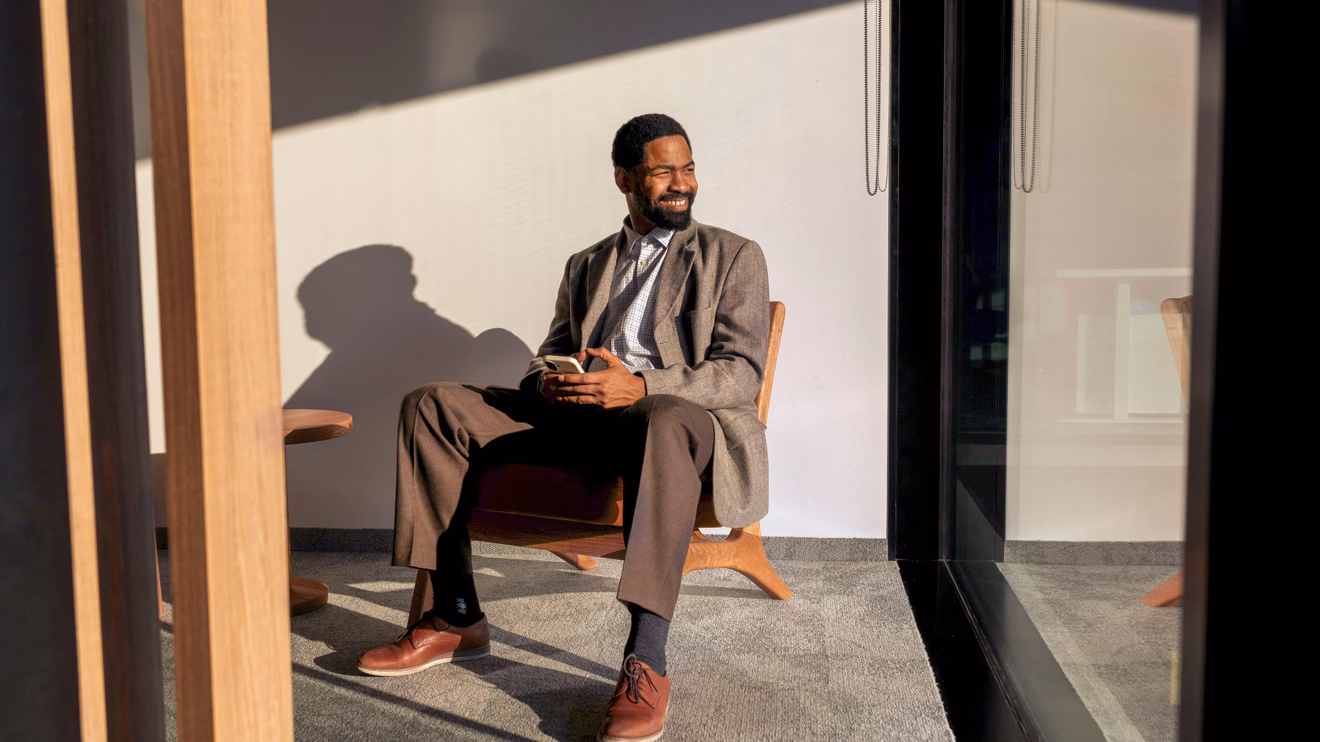 Un homme en costume est assis dans un bureau lumineux et tient un smartphone.