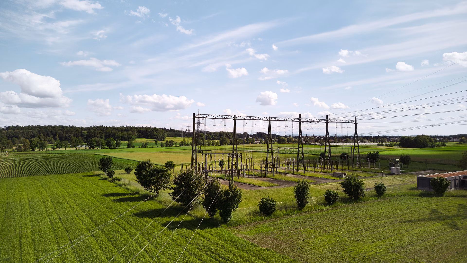 Substation with overhead lines in a green agricultural landscape under a blue sky